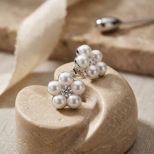 Pearl flower-shaped earrings on a beige stone surface