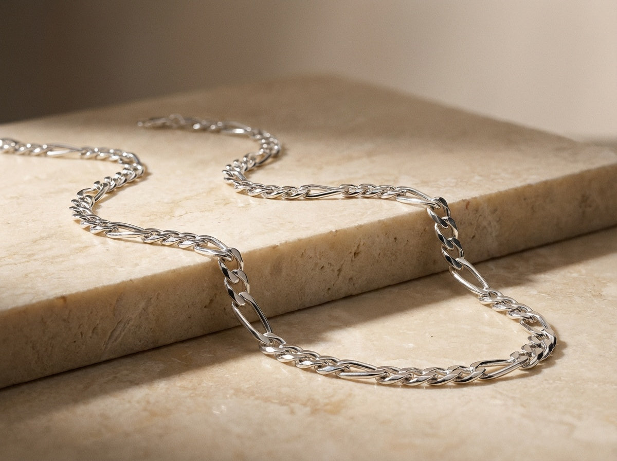 Silver chain necklace on a beige stone surface