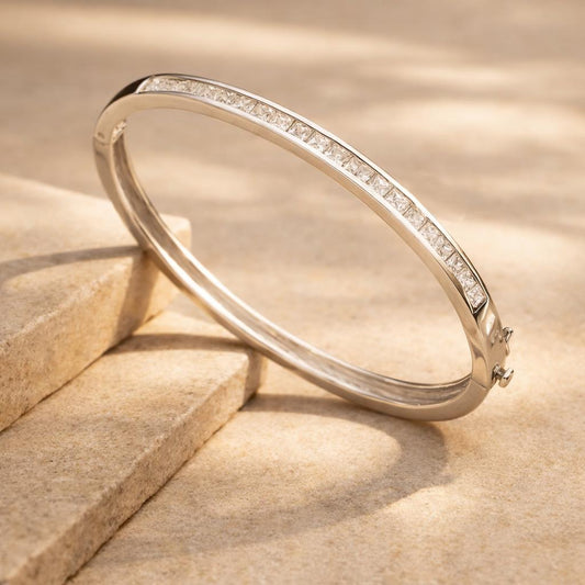 A Square Channel Set Bangle with Cubic Zirconia with diamonds on a beige stone surface