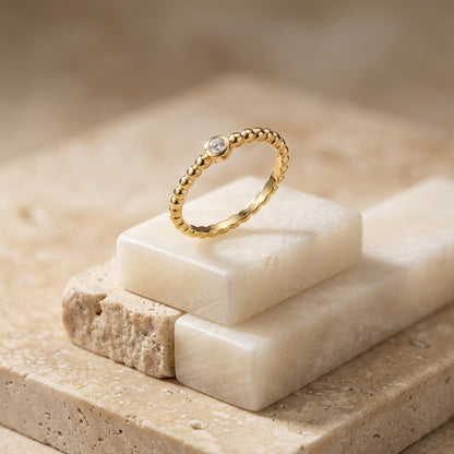 Gold ring with a diamond on a stone surface