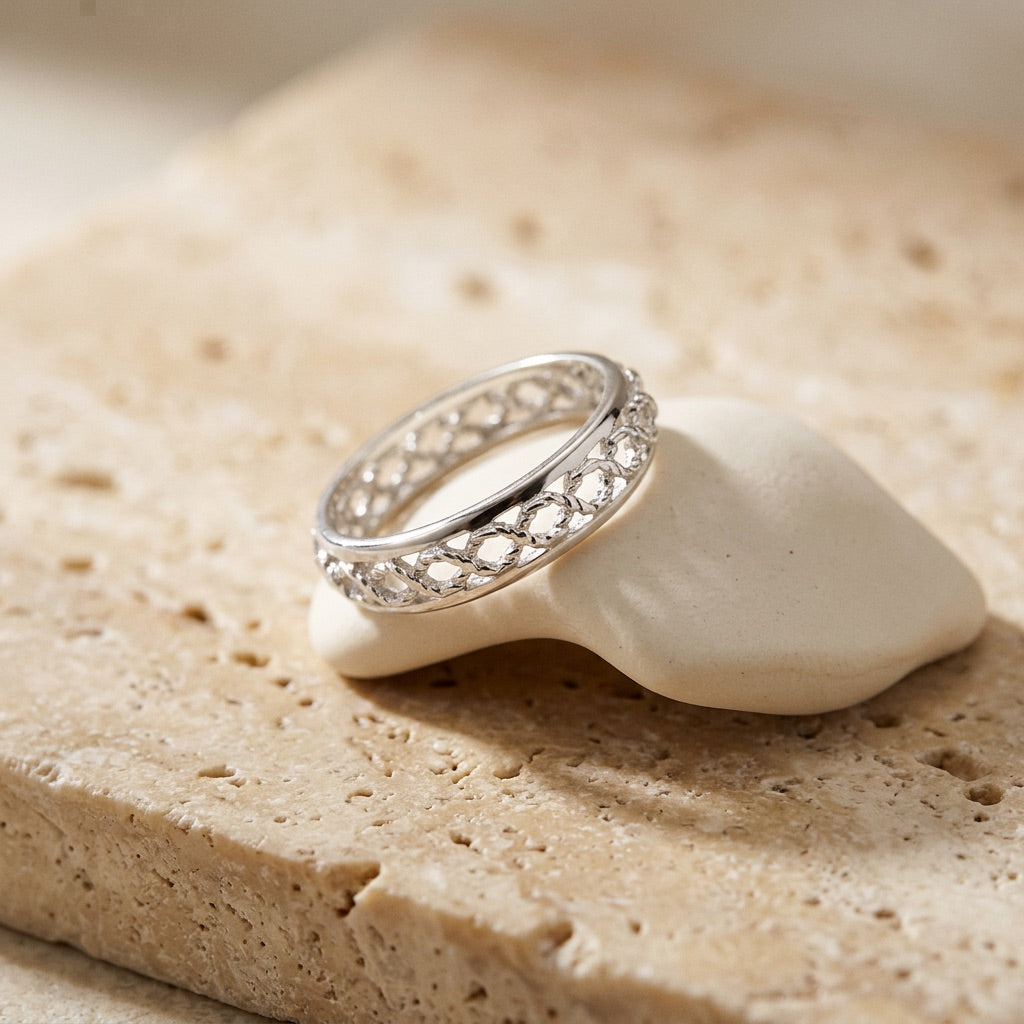 Silver ring with gemstones on a white shell against a beige stone background