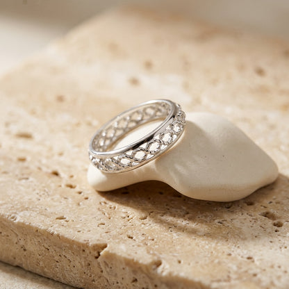 Silver ring with gemstones on a white shell against a beige stone background