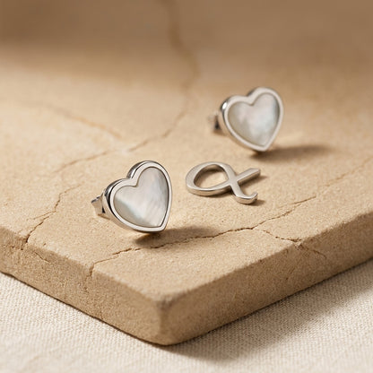 Spectrum Dinky White Mother of Pearl Heart Stud Earrings on a textured beige surface