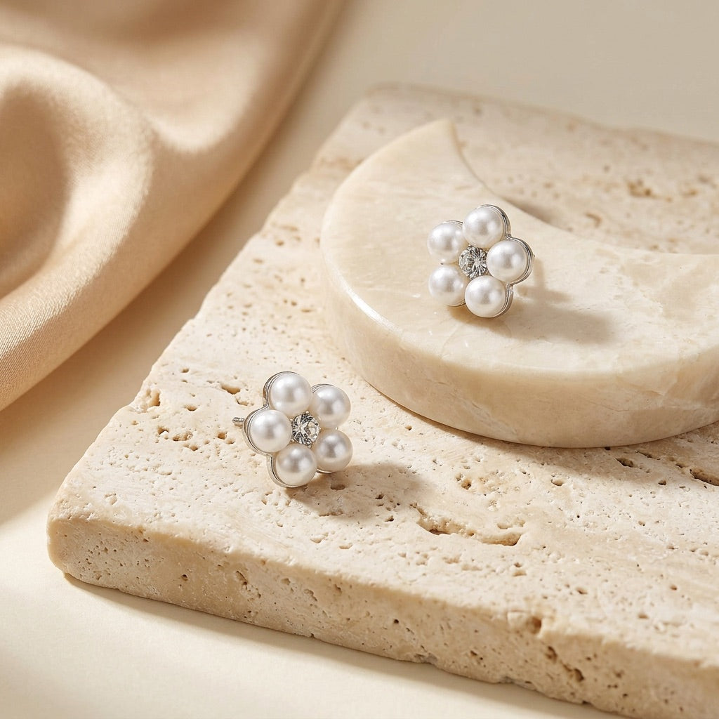 Pair of pearl earrings on a stone surface with a soft beige background