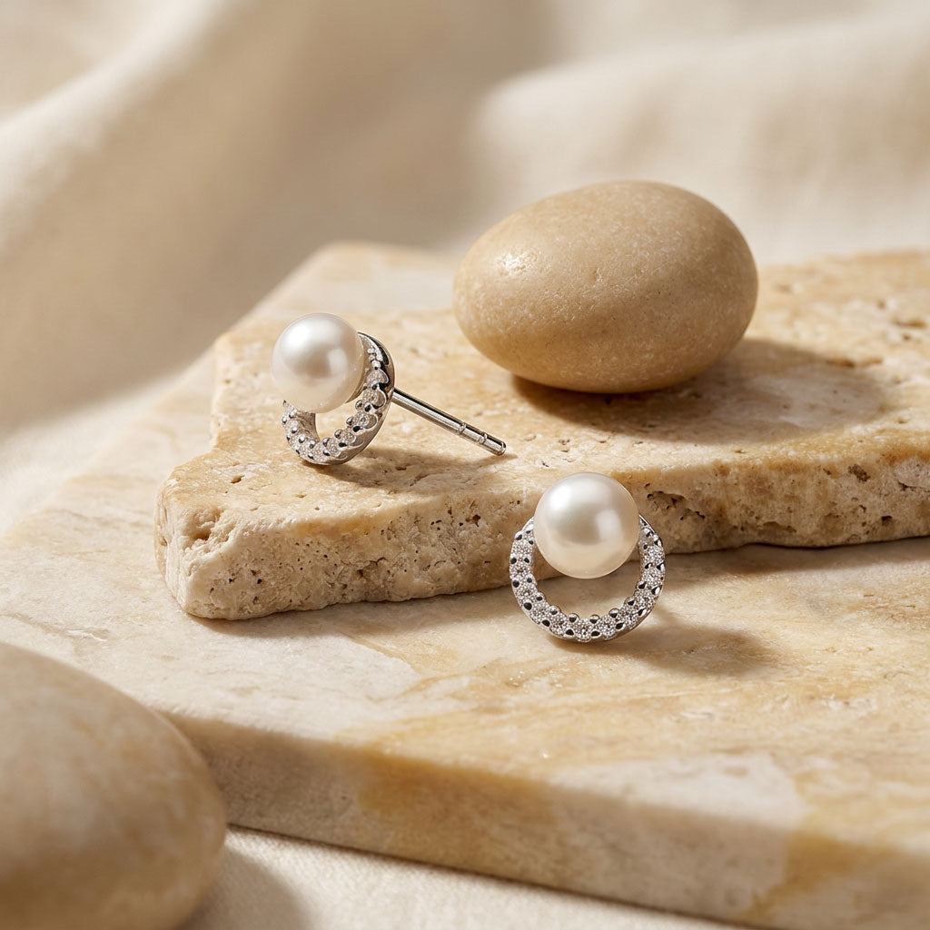 Pearl earrings on a stone surface with a natural light background
