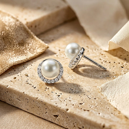 Pearl earrings with diamond accents on a beige stone surface