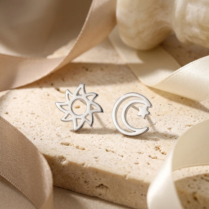 Silver sun and moon earrings on a beige fabric background