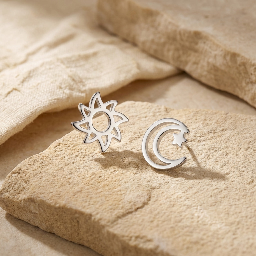 Silver sun and moon earrings on a beige stone surface