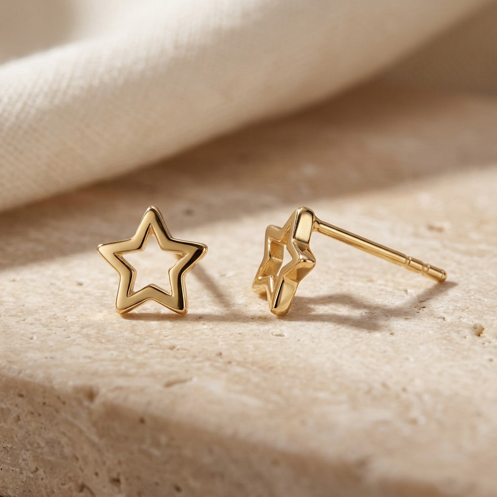 Gold star-shaped earrings on a beige fabric background