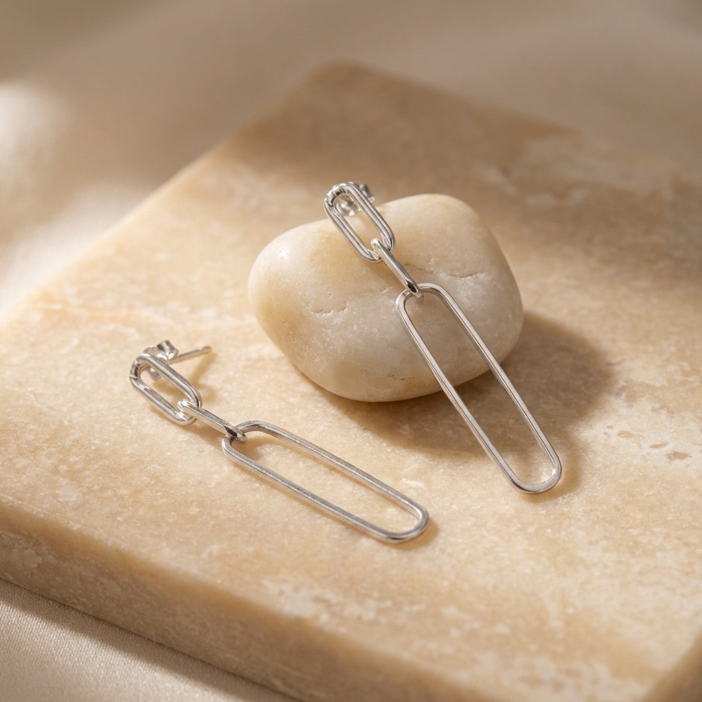 Silver earrings on a stone surface with a soft background