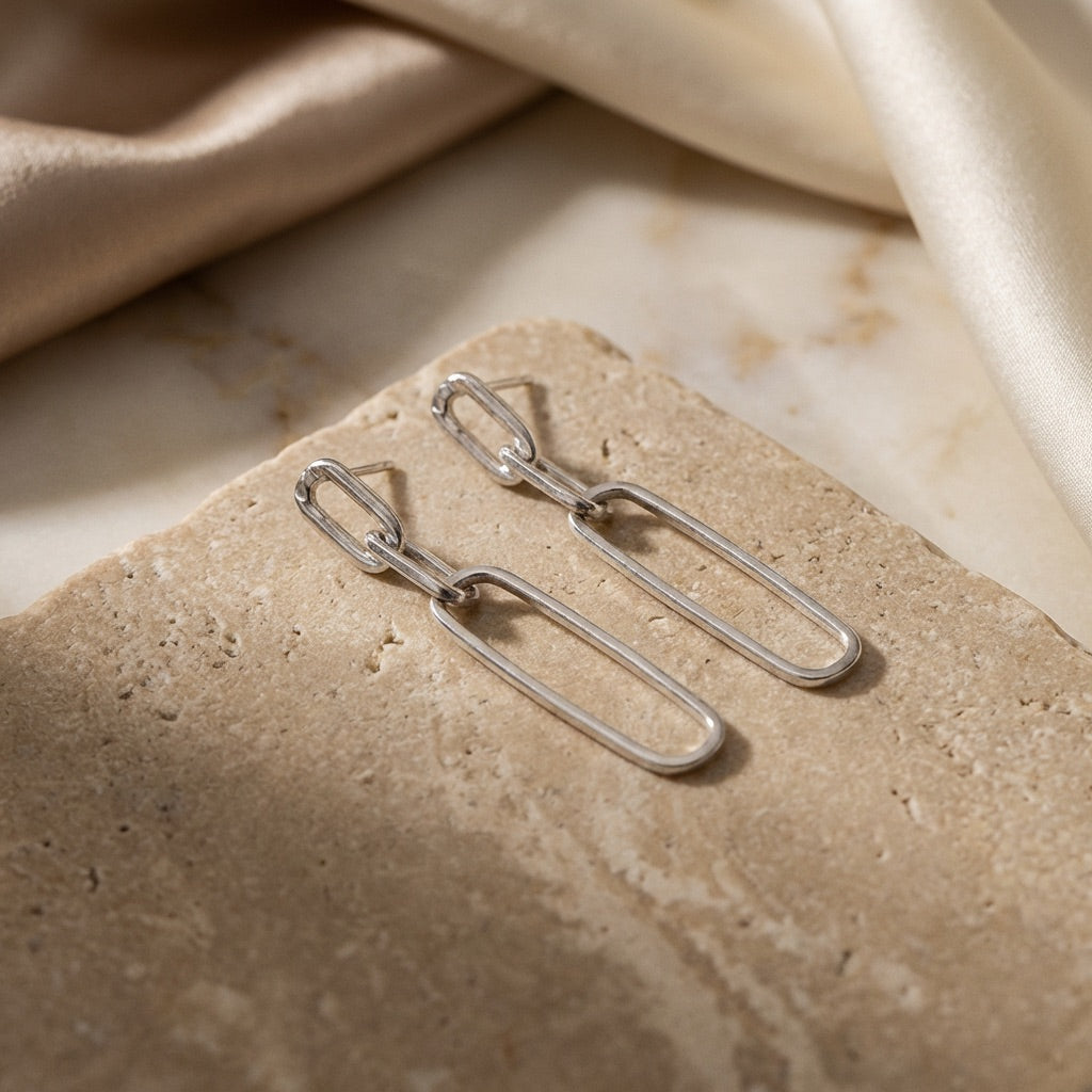 Silver earrings on a textured beige surface