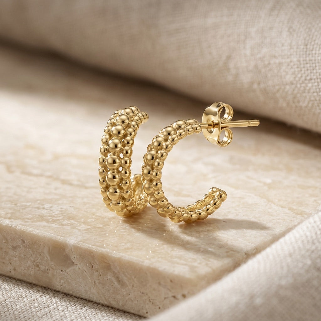 Gold Plate 13mm Triple Beaded Stud Hoop Earrings . on a beige stone surface