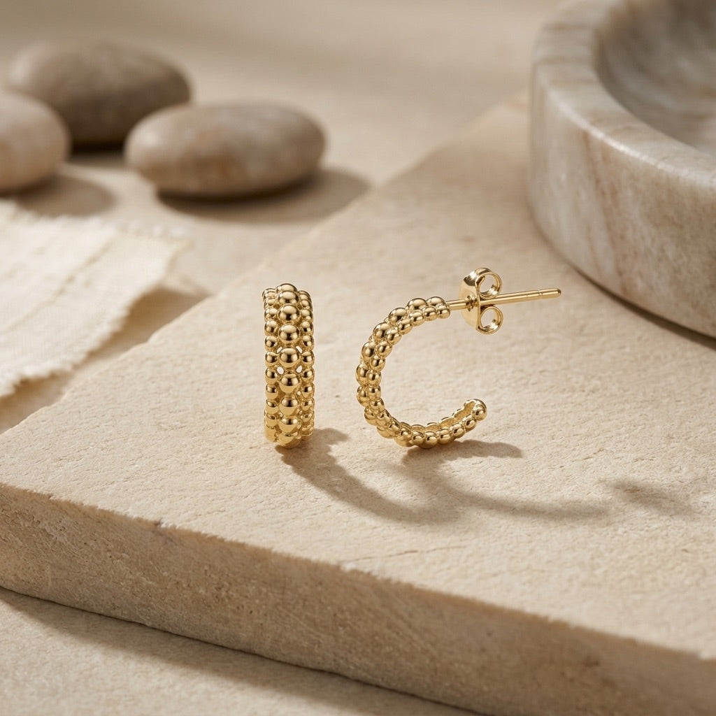 Gold Plate 13mm Triple Beaded Stud Hoop Earrings on a textured beige surface with stones in the background