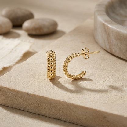 Gold Plate 13mm Triple Beaded Stud Hoop Earrings on a textured beige surface with stones in the background