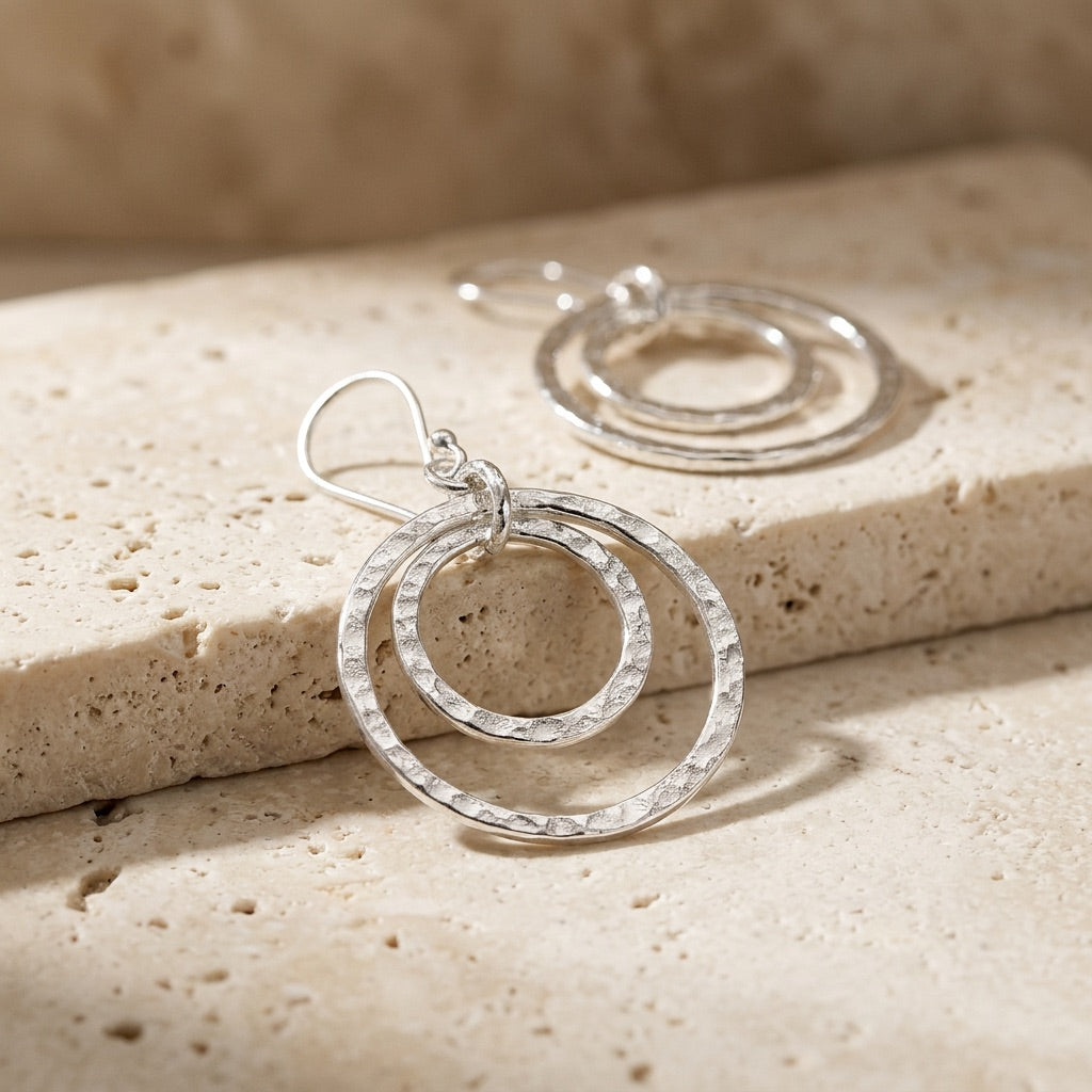 Silver hoop earrings on a textured beige surface