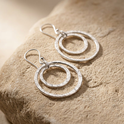 Double Hammered Circle Drop Earrings on a textured beige surface