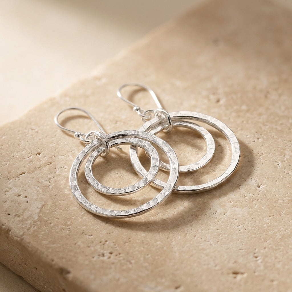 Double Hammered Circle Drop Earringson a beige stone surface
