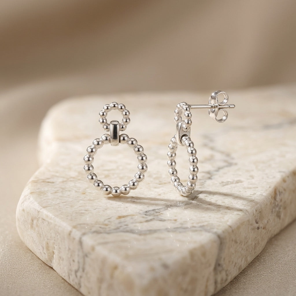 Silver Beaded Circle Link Drop Earrings on a marble surface with a neutral background
