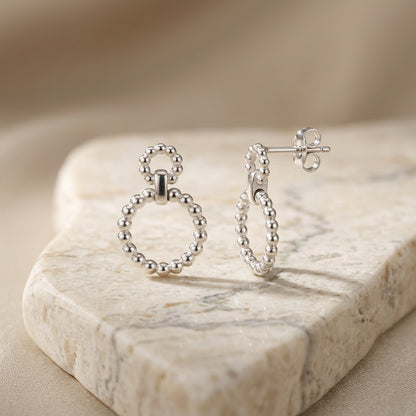 Silver Beaded Circle Link Drop Earrings on a marble surface with a neutral background