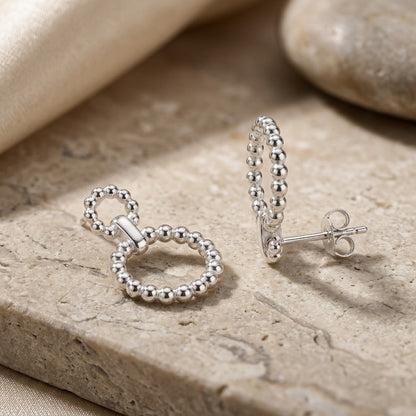 Silver Beaded Circle Link Drop Earrings on a stone surface