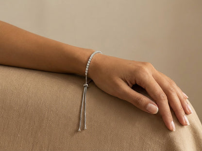 Hand wearing a silver bracelet on a beige background