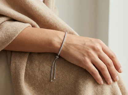 Close-up of a hand wearing a bracelet on a neutral background