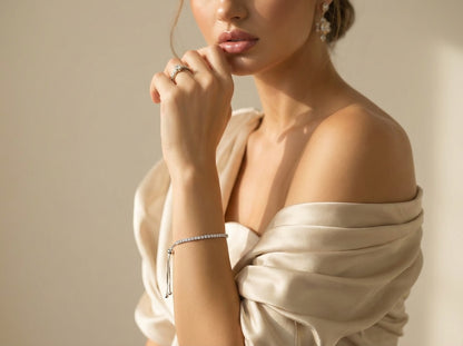 Woman wearing a beige off-shoulder top with jewelry on a neutral background