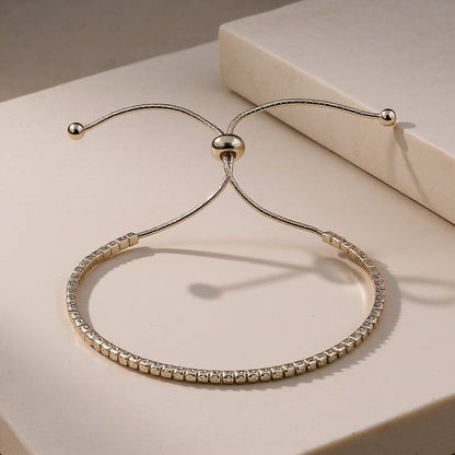 Gold bracelet with clear stones on a beige surface