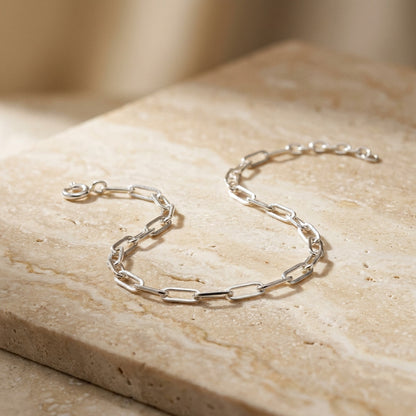Silver chain bracelet on a beige stone surface
