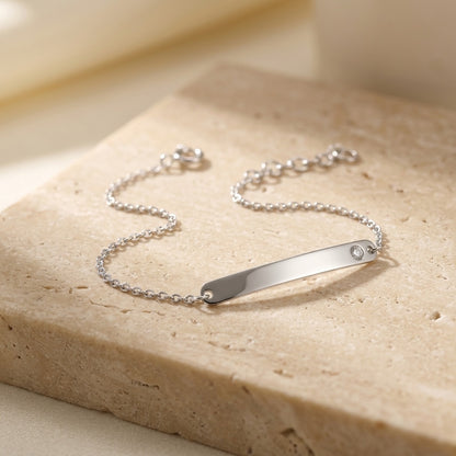 Classic ID Tag with Flush Set Cubic Zirconia 7” Bracelet on a beige stone surface
