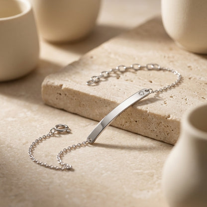 Classic ID Tag with Flush Set Cubic Zirconia 7” Bracelet on a stone surface with ceramic cups in the background