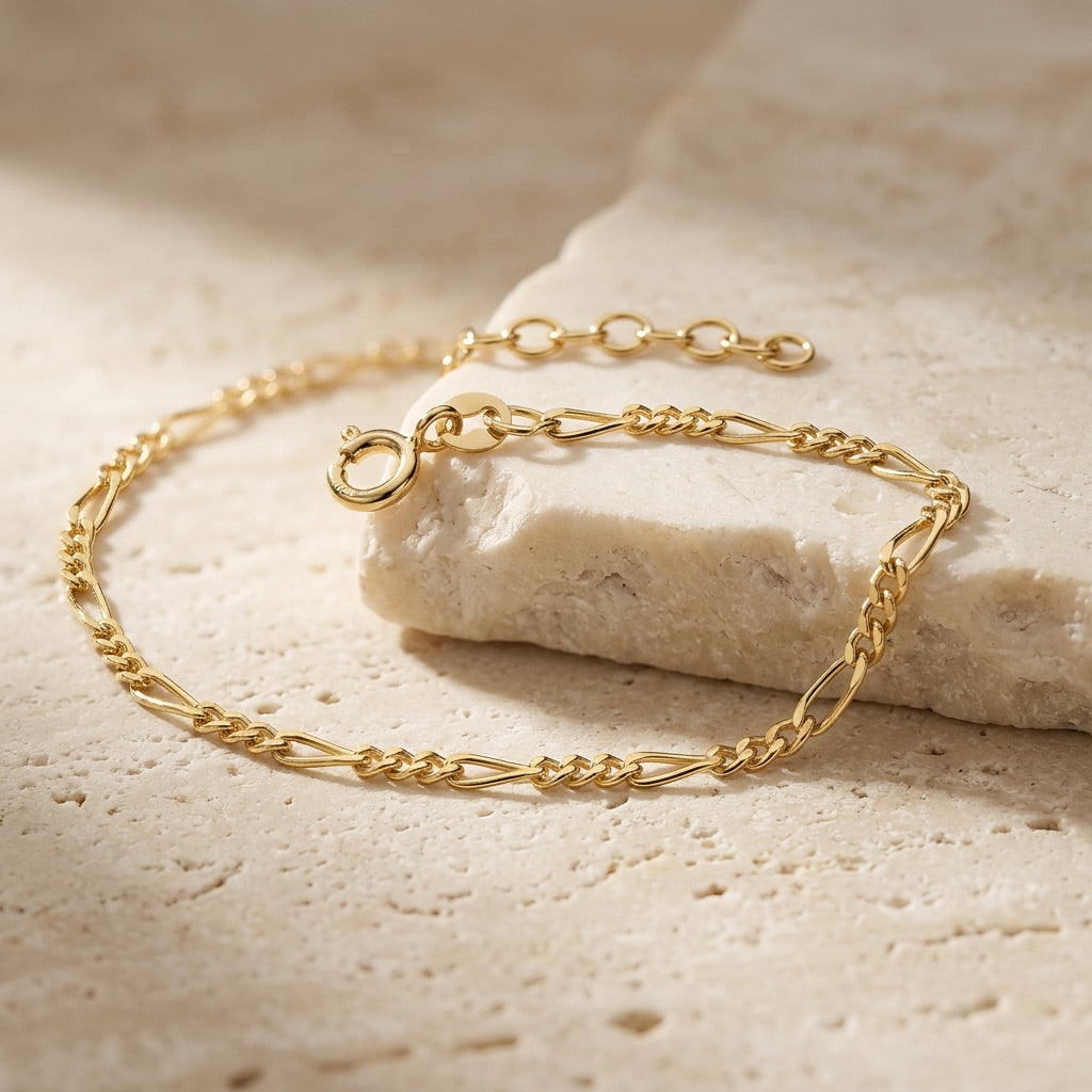 Gold chain bracelet on a textured beige surface