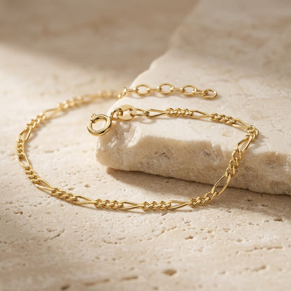 Gold chain bracelet on a textured beige surface