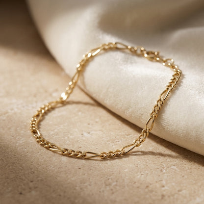 Golden Figaro Gold Plate Bracelet on a beige surface