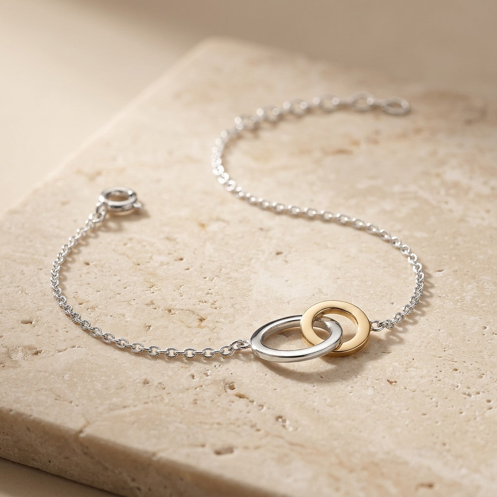 Silver bracelet with gold rings on a beige stone surface