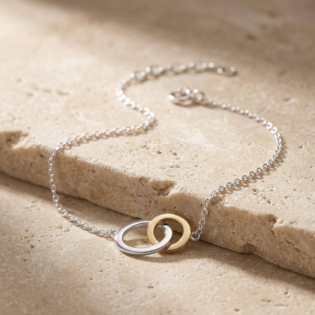 Silver and gold necklace on a textured beige surface