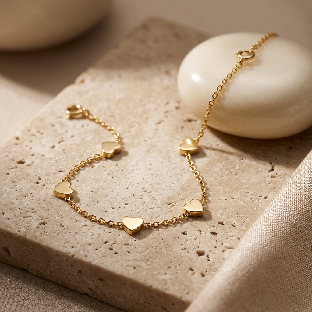 Gold bracelet with heart-shaped charms on a textured surface