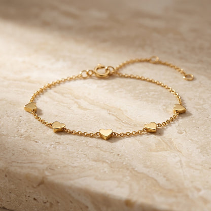 Golden Gold Plate Heart Station Bracelet on a beige stone surface