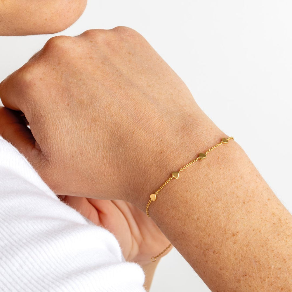Golden Gold Plate Heart Station Bracelet on a wrist with a plain background