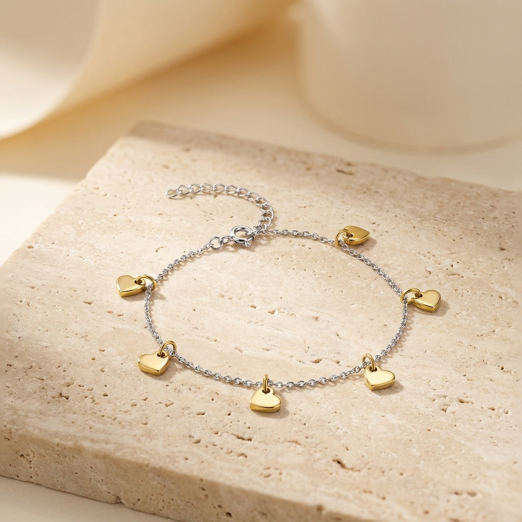 Anklet with gold heart charms on a beige stone surface