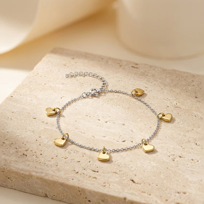 Anklet with gold heart charms on a beige stone surface