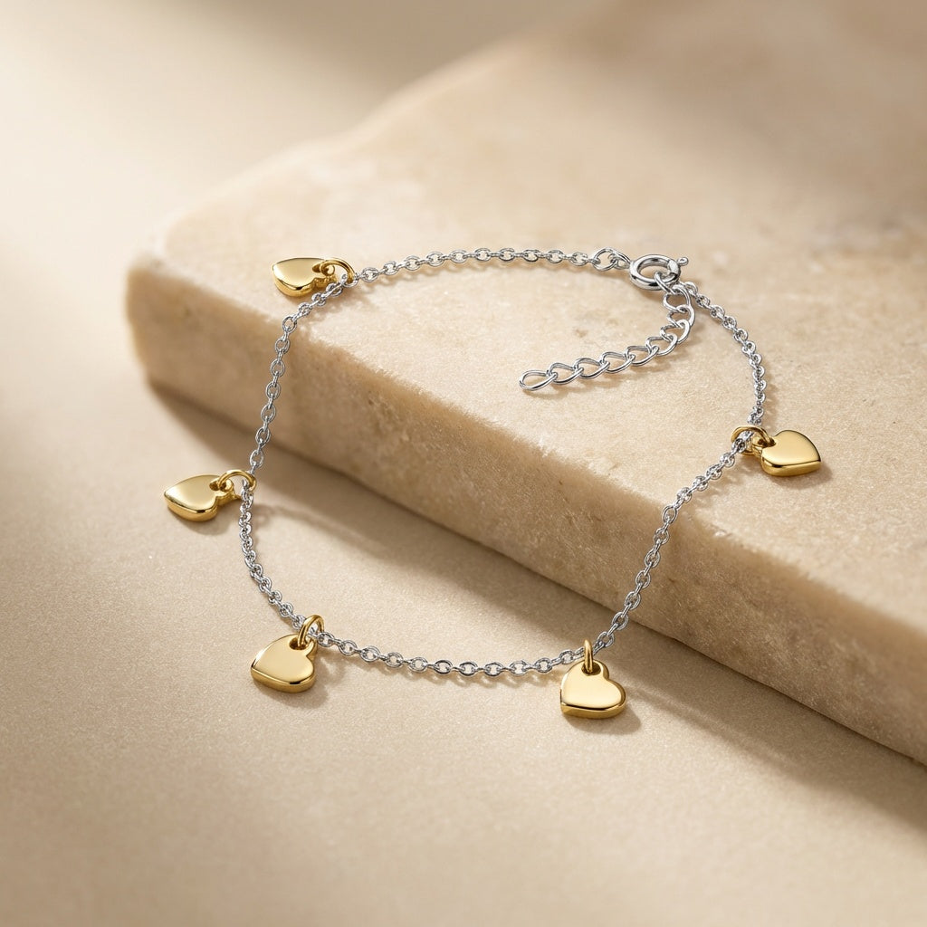 Anklet with gold heart charms on a beige stone surface