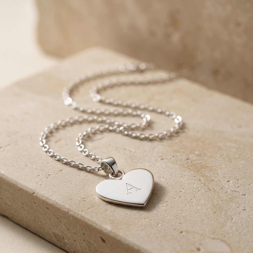 Silver heart-shaped pendant necklace on a beige surface