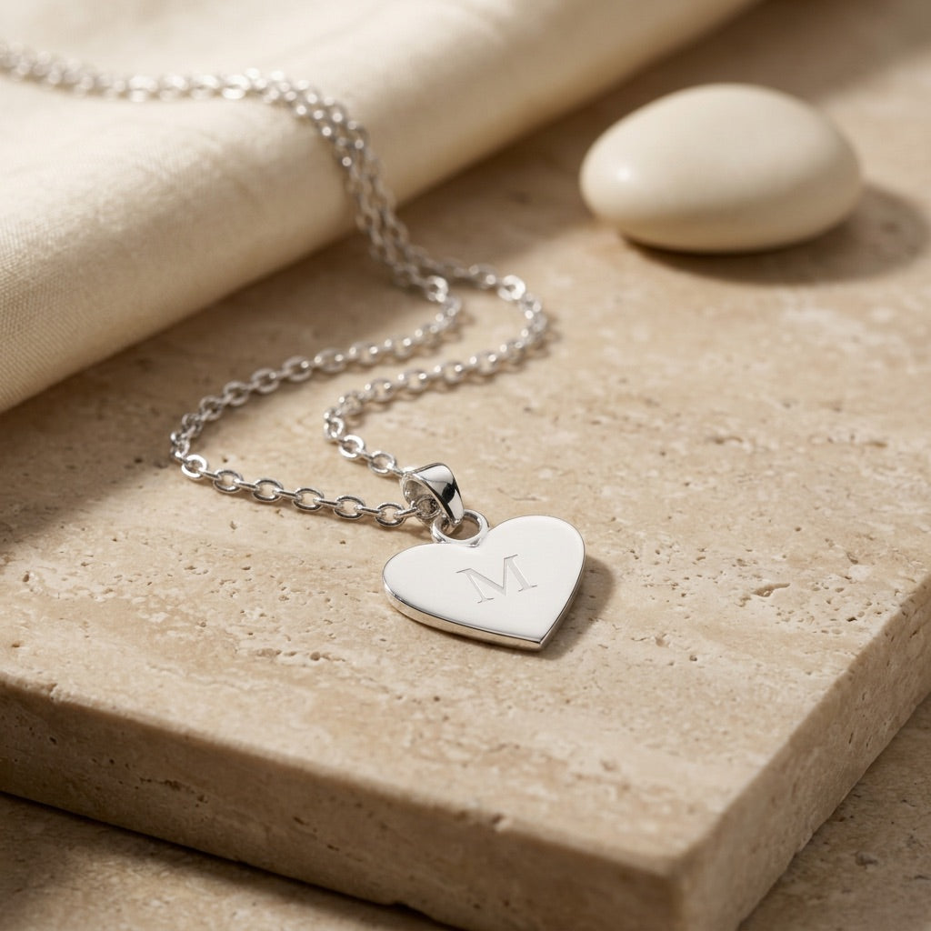 Silver heart-shaped pendant necklace on a beige surface