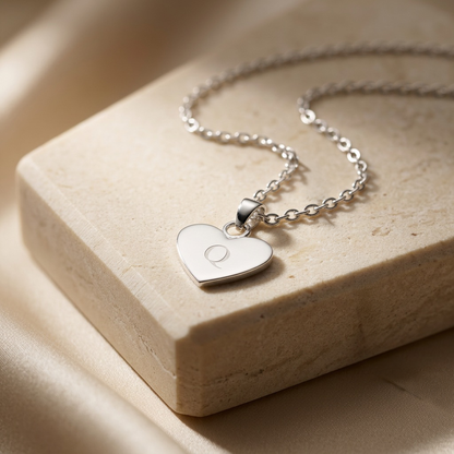 Silver heart-shaped pendant necklace on a beige stone surface