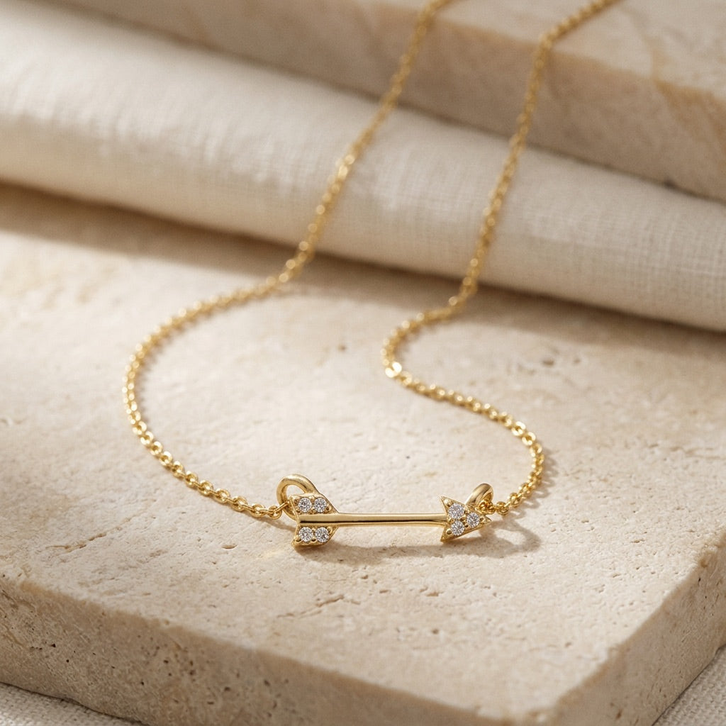 Gold bracelet with an arrow design on a beige stone surface