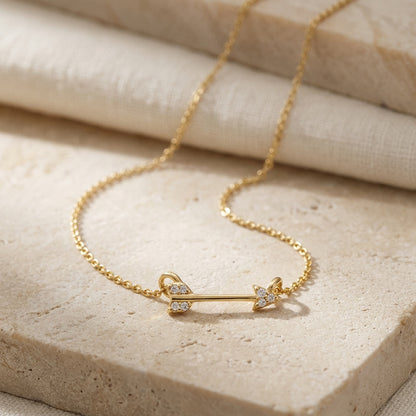 Gold bracelet with an arrow design on a beige stone surface