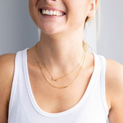 Woman wearing a Golden Pavé Cubic Zirconia Arrow 18” Necklet with a plain background