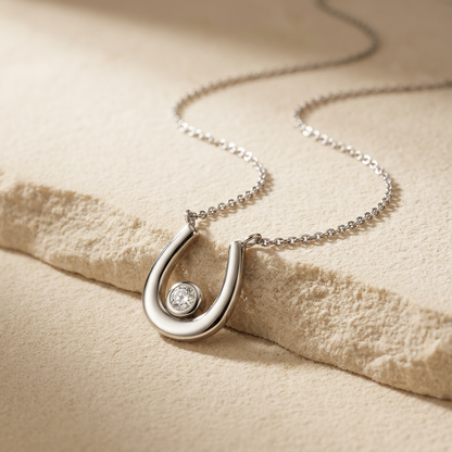 Cubic Zirconia Horseshoe Silver Necklet on a beige textured surface