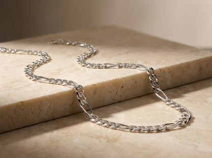 Silver chain necklace on a beige stone surface